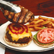 A pork chop tops a cheeseburger.